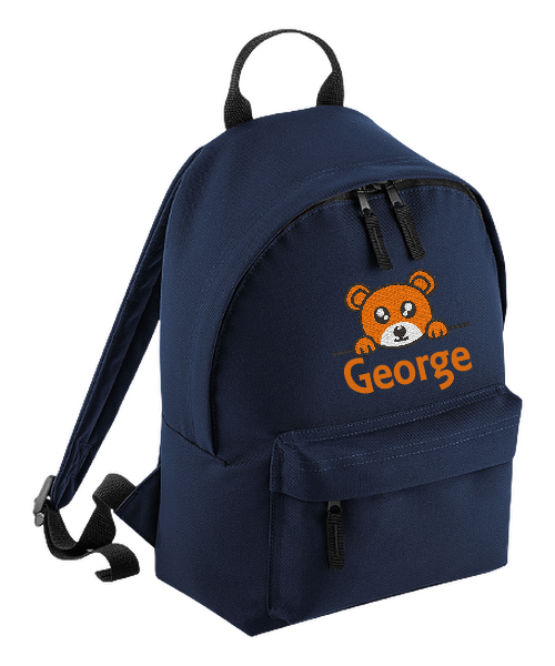 Introducing the fabulously fashionable, petite-sized Personalised Mini School Backpack! It's got it all: a nifty zippered front pocket, extra-cushy back panel and adjustable shoulder straps, plus a handy grab handle to boot!  Colour - Navy Blue Rucksack Dimensions - 24 x 33 x 17cm. Capacity 9 litres.  Choose between 4 colours - Jet Black, Jungle Camo, Navy Blue, Pretty in Pink!  Personalisation comes complimentary - no extra cost!