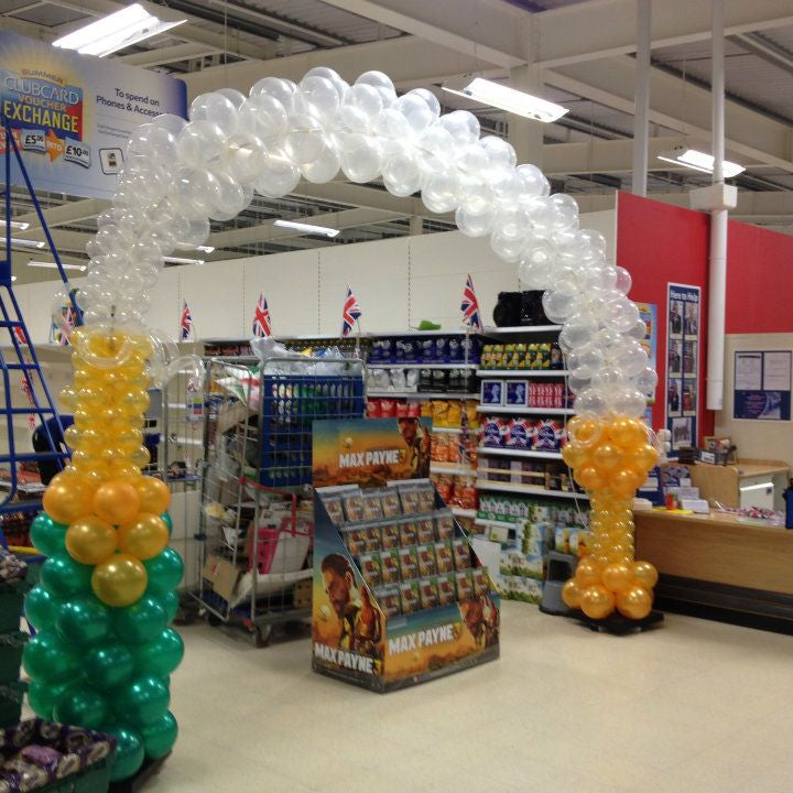 Balloon champagne bottle, bubbles and champagne glass in a store with product displays and promotional signs.